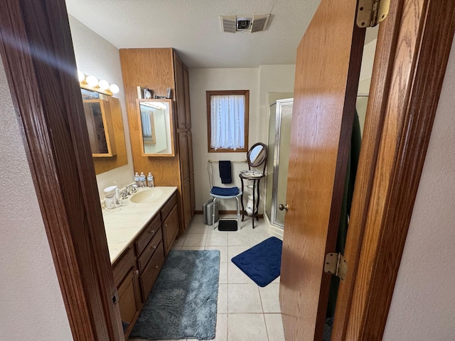 bathroom with vanity, tile patterned floors, a shower with door, and a textured ceiling