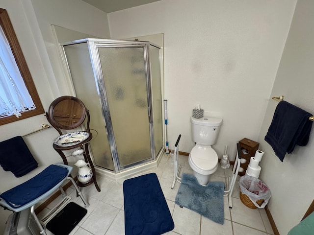 bathroom featuring a shower with shower door, tile patterned floors, and toilet