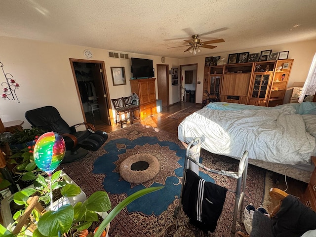 bedroom with ceiling fan, a textured ceiling, a spacious closet, and a closet