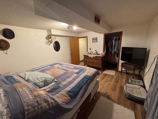 bedroom featuring hardwood / wood-style flooring, a textured ceiling, and a closet