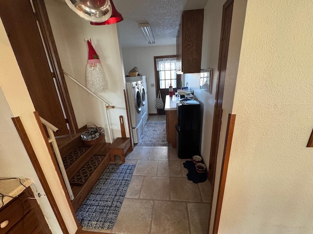 clothes washing area with a textured ceiling and separate washer and dryer