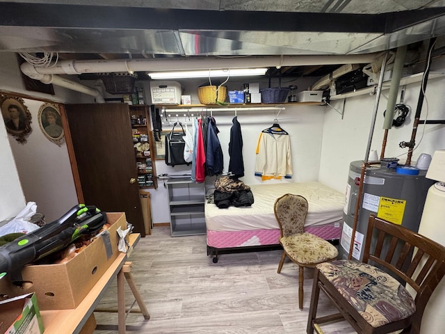 basement featuring electric water heater and light hardwood / wood-style floors