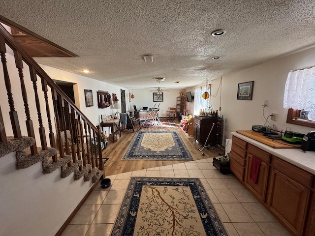 interior space featuring ceiling fan, light tile patterned flooring, and a textured ceiling