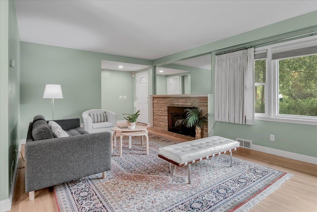 living room with light wood-type flooring and a stone fireplace