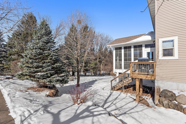 snowy yard with a sunroom and stairs