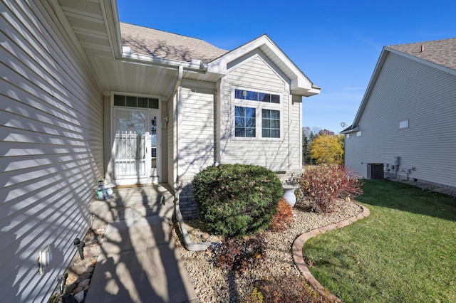 entrance to property with a yard and central air condition unit