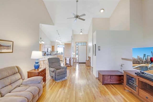 living room with light hardwood / wood-style flooring, high vaulted ceiling, and ceiling fan with notable chandelier