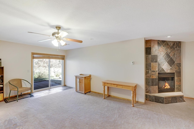 interior space featuring a tiled fireplace, ceiling fan, and carpet