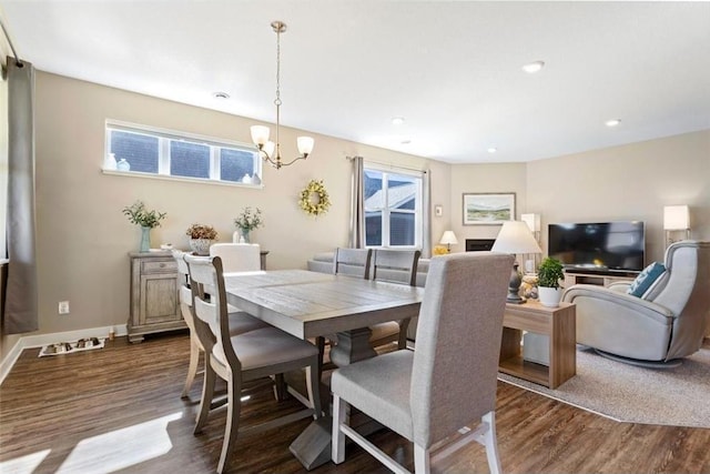 dining space with dark hardwood / wood-style floors and an inviting chandelier