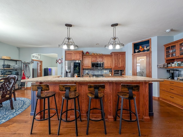 kitchen featuring decorative backsplash, appliances with stainless steel finishes, wood-type flooring, and a kitchen island