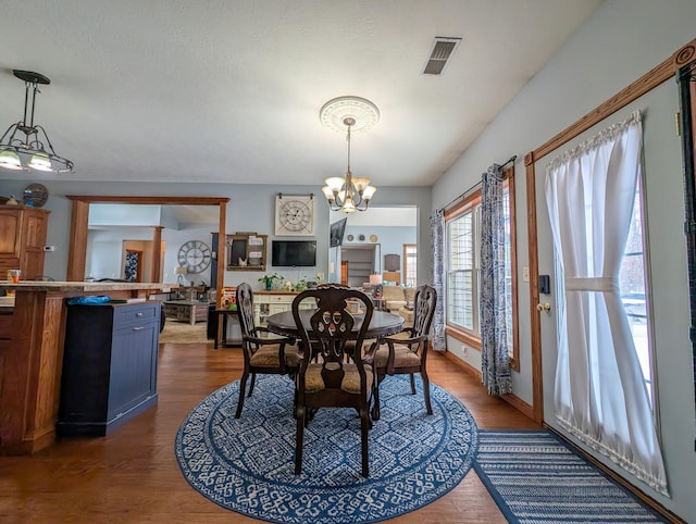 dining space with dark wood-type flooring and a notable chandelier