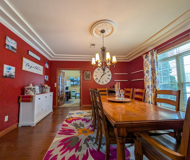 dining space featuring dark wood-type flooring, ornamental molding, and a notable chandelier