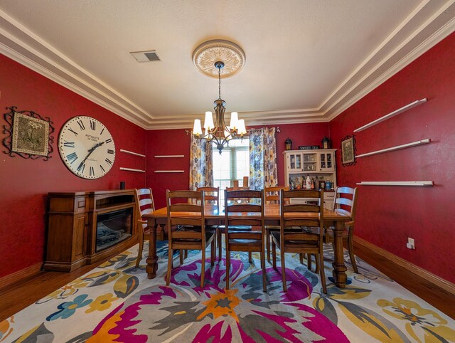 dining room featuring hardwood / wood-style flooring, ornamental molding, and a notable chandelier