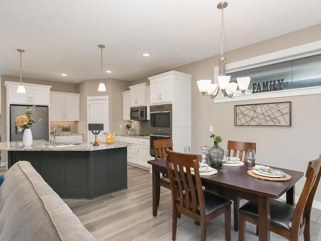 kitchen featuring stainless steel appliances, white cabinets, pendant lighting, and sink