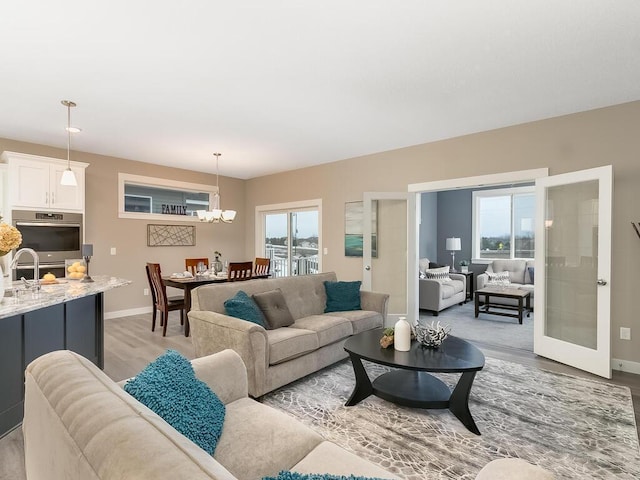 living room featuring light hardwood / wood-style floors, french doors, and a chandelier