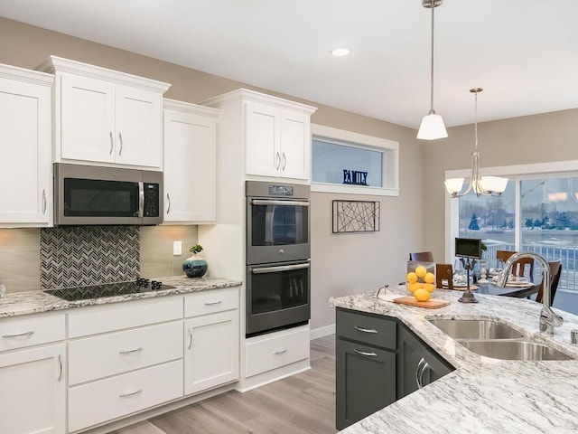 kitchen with stainless steel appliances, decorative backsplash, sink, white cabinetry, and decorative light fixtures