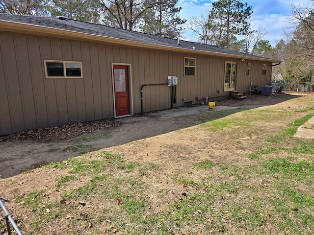 rear view of property with fence, cooling unit, entry steps, and roof with shingles