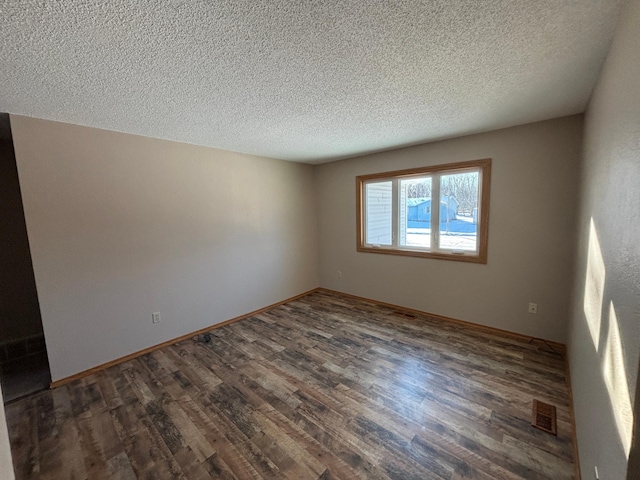 unfurnished room with dark hardwood / wood-style flooring and a textured ceiling