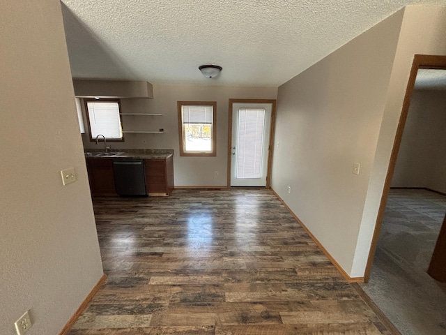 interior space featuring dishwasher, dark wood-type flooring, sink, and a textured ceiling