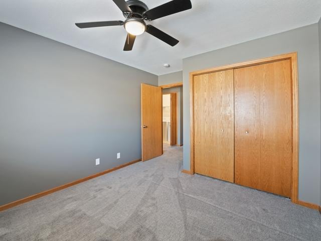 unfurnished bedroom featuring ceiling fan, light colored carpet, and a closet