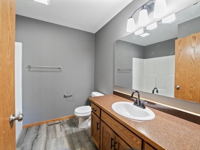 bathroom with walk in shower, toilet, vanity, and wood-type flooring