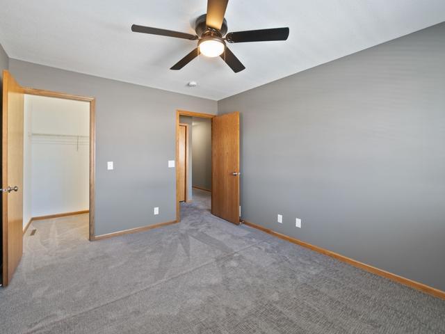 unfurnished bedroom featuring light carpet, a closet, ceiling fan, and a spacious closet