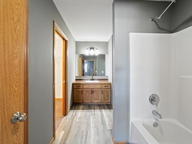 bathroom with shower / washtub combination, hardwood / wood-style floors, and vanity