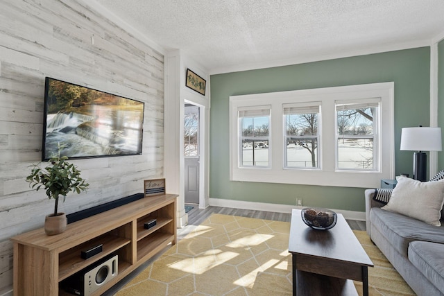 living area with baseboards, a textured ceiling, and wood walls