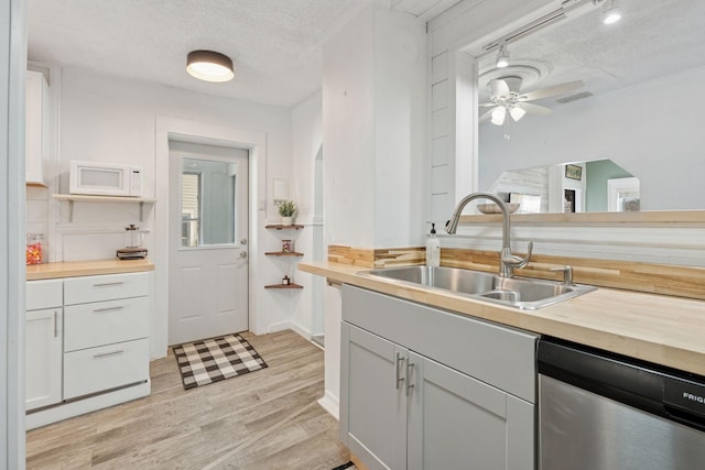 kitchen with wooden counters, white microwave, dishwasher, and a sink