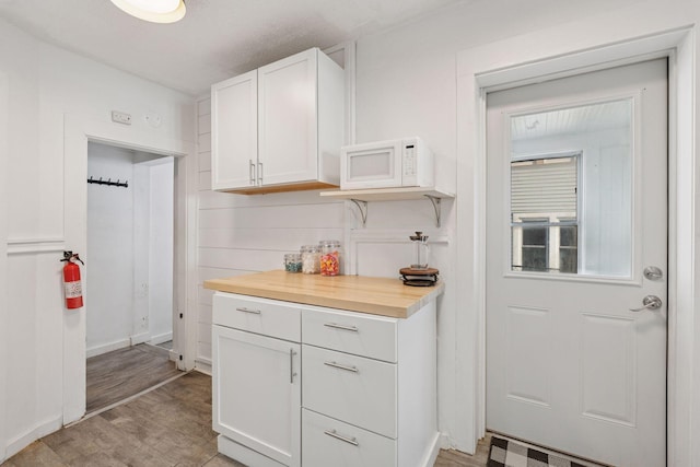 kitchen featuring visible vents, light wood-style flooring, white cabinetry, light countertops, and white microwave