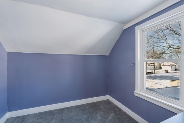 additional living space featuring baseboards, dark carpet, and vaulted ceiling