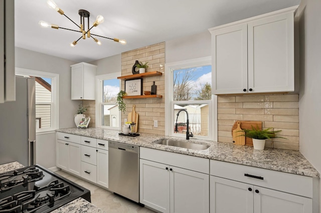 kitchen with stainless steel appliances, white cabinets, tasteful backsplash, and sink