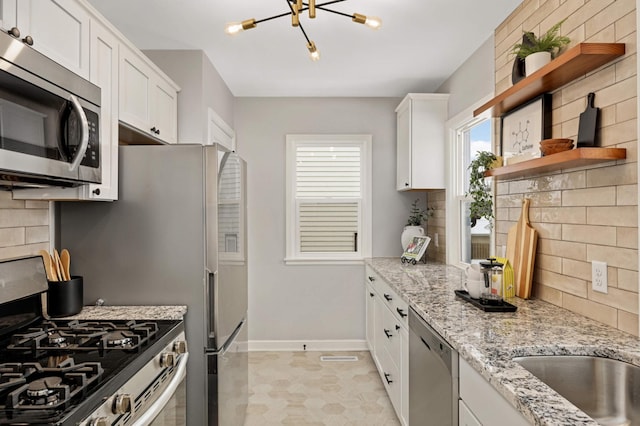 kitchen featuring appliances with stainless steel finishes, backsplash, white cabinets, and light stone countertops