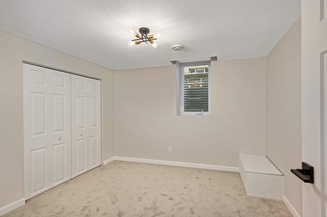 unfurnished bedroom with light colored carpet, a textured ceiling, and a closet