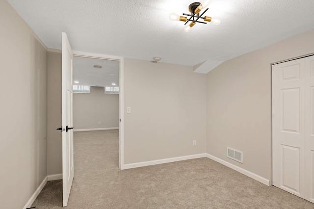 unfurnished bedroom with light colored carpet, a closet, and a textured ceiling