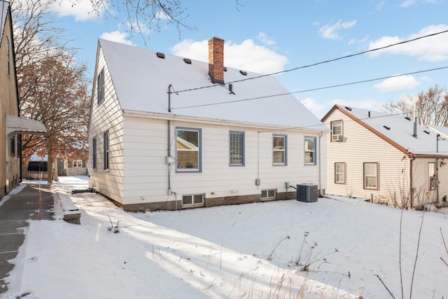 snow covered rear of property featuring central AC