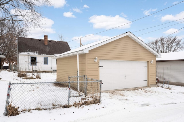 view of snowy exterior featuring a garage and an outbuilding