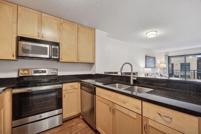 kitchen featuring sink, a textured ceiling, light brown cabinets, appliances with stainless steel finishes, and dark hardwood / wood-style floors