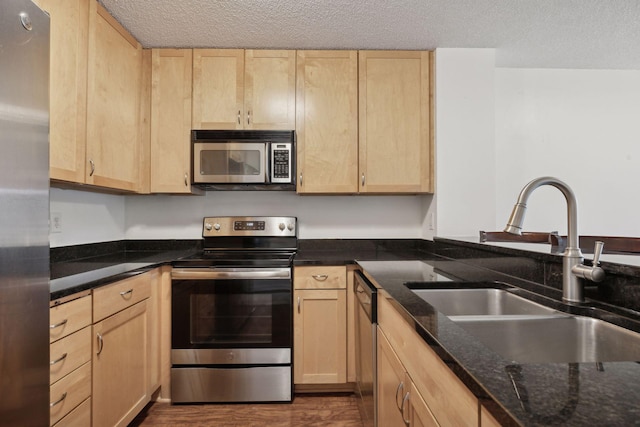 kitchen featuring appliances with stainless steel finishes, light brown cabinetry, and sink