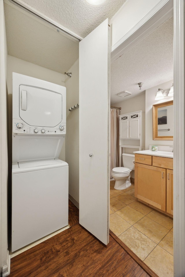 washroom featuring stacked washer / drying machine, dark hardwood / wood-style floors, and a textured ceiling