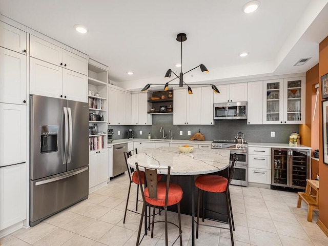 kitchen featuring appliances with stainless steel finishes, decorative light fixtures, sink, white cabinets, and wine cooler