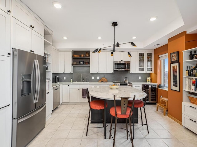 kitchen with pendant lighting, sink, appliances with stainless steel finishes, wine cooler, and a kitchen island