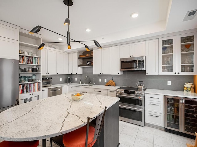 kitchen featuring wine cooler, white cabinetry, a center island, pendant lighting, and stainless steel appliances