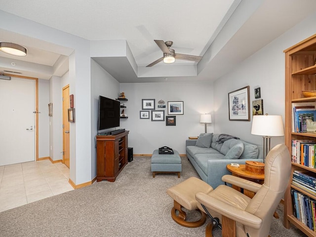 carpeted living room with a raised ceiling and ceiling fan