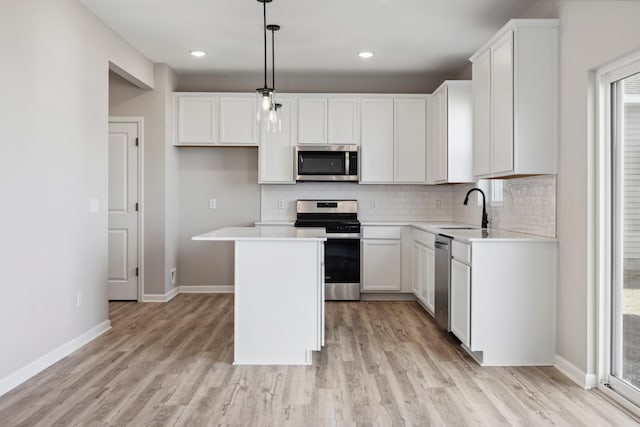 kitchen featuring appliances with stainless steel finishes, a center island, hanging light fixtures, white cabinets, and sink