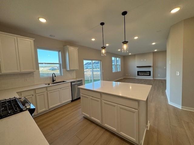 kitchen with sink, white cabinets, a center island, dishwasher, and light wood-type flooring