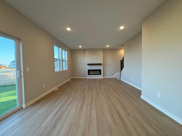 unfurnished living room featuring a wealth of natural light and light hardwood / wood-style flooring