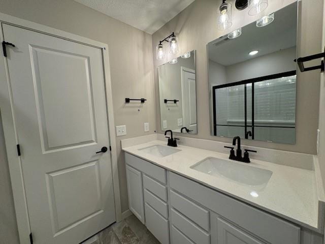 bathroom with a textured ceiling, a shower with door, and vanity