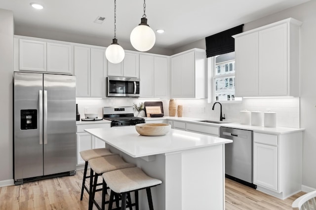 kitchen featuring stainless steel appliances, a kitchen island, white cabinets, and sink