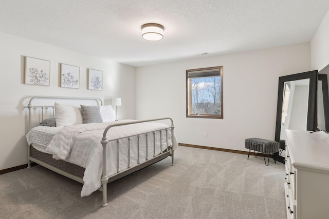 bedroom featuring light colored carpet and a textured ceiling